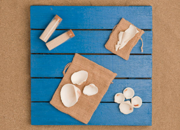 beach scene top view, boats with beach sand and sea shells on rustic cloth sacks