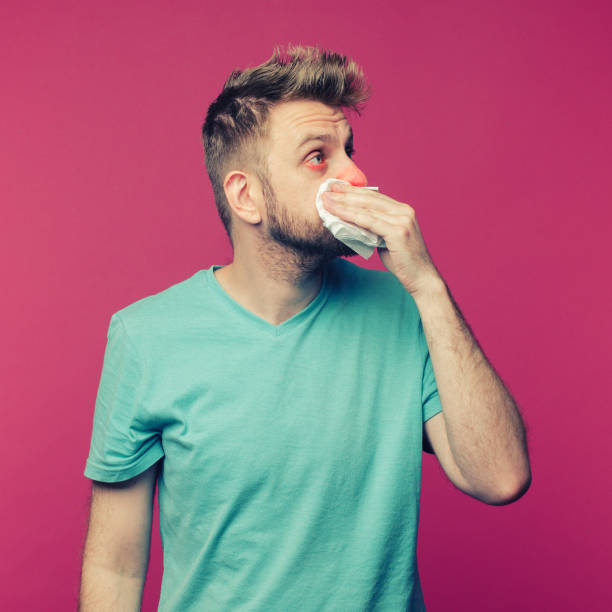 istock studio picture from a young man with handkerchief. Sick guy isolated has runny nose. man makes a cure for the common cold 1255054974