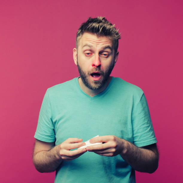 istock studio picture from a young man with handkerchief going to sneeze. Sick guy isolated has runny nose. man makes a cure for the common cold 1255055103