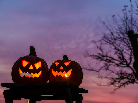 Two pumpkins as Halloween Jack O' lantern in front of a sunset