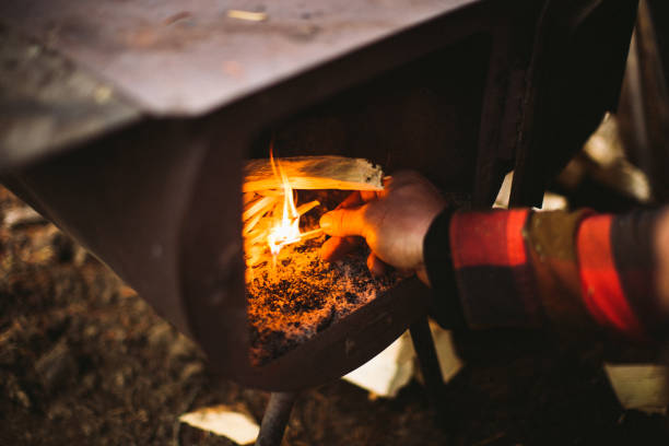 istock Man lighting a fire in an old wood stove 1255056744