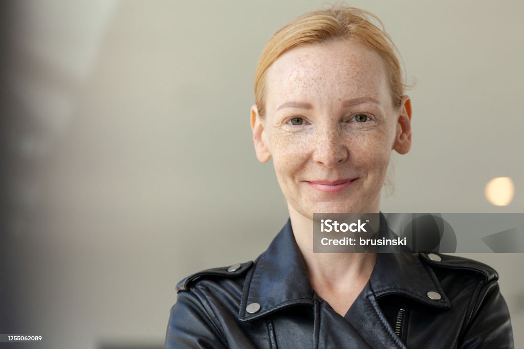 outdoors portrait of a 45 year old red-haired woman outdoors closeup portrait of a 45 year old red-haired woman in a black leather jacket Women Stock Photo