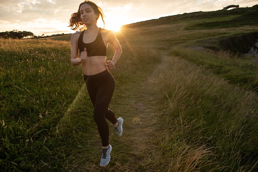 a young woman running outdoors at sunset time in the region of Cantabria in Northern Spain.