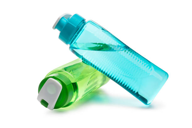 botella de agua azul y verde apoyada en cada uno aislado sobre un fondo blanco - coloured bottles fotografías e imágenes de stock