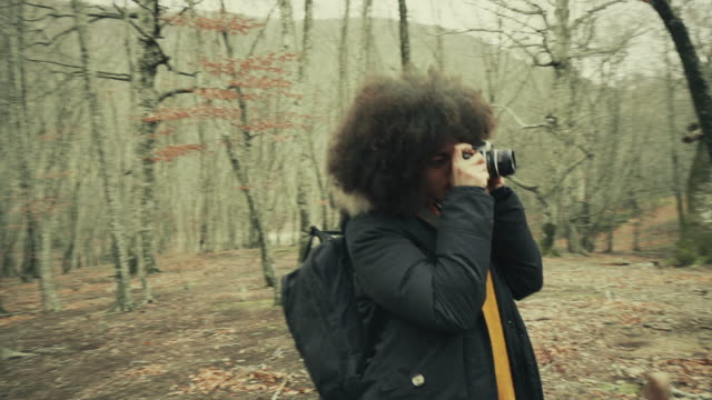 Young woman with afro hairstyle in the woods: autumn winter colors