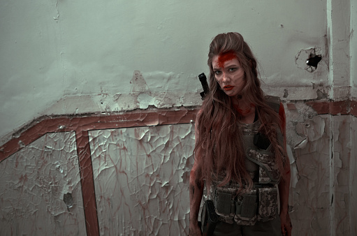Angry warrior standing in front of damaged wall, looking at the camera feeling angry and full of blood