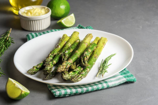 istock Appetizingly cooked asparagus with pieces of lime on a grey concrete table. 1255069313