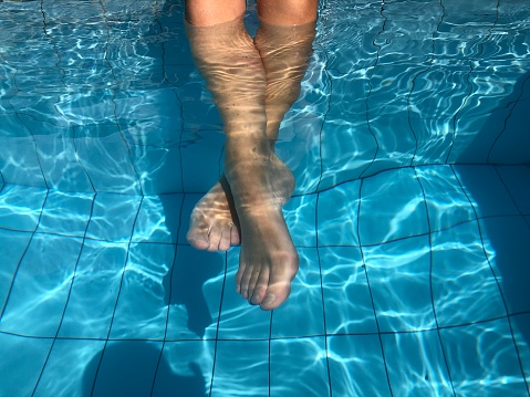 Close up underwater woman feet in swimming pool.Summer holiday concept.