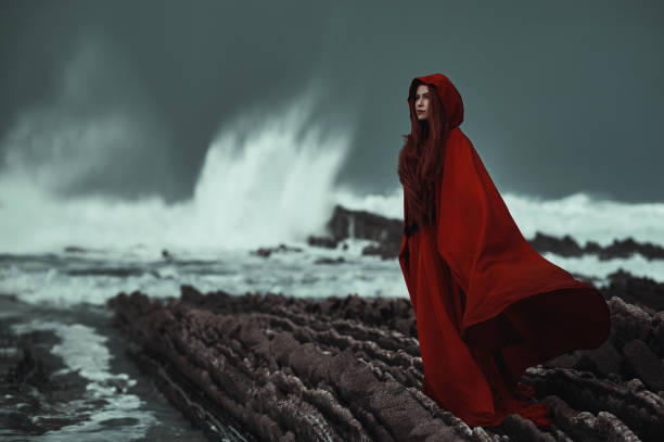 donna misteriosa che indossa il rosso sulla costa - cliffside foto e immagini stock