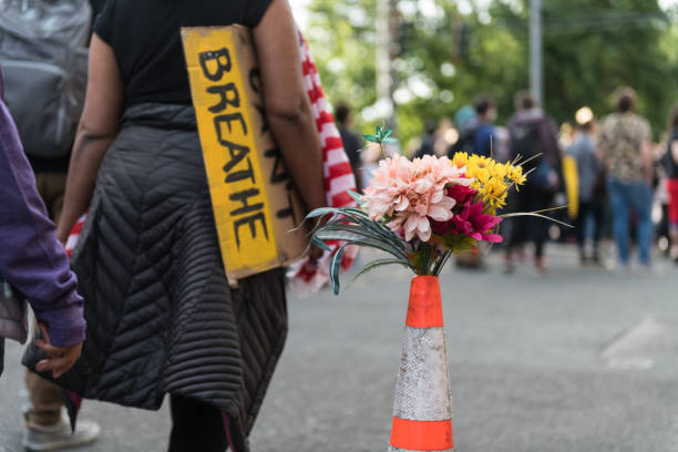 Seattle Seattle, USA – Jun 4, 2020: Flowers at the Autonomous zone late in the day on Capitol Hill as a person passes with a sign. george floyd protests stock pictures, royalty-free photos & images