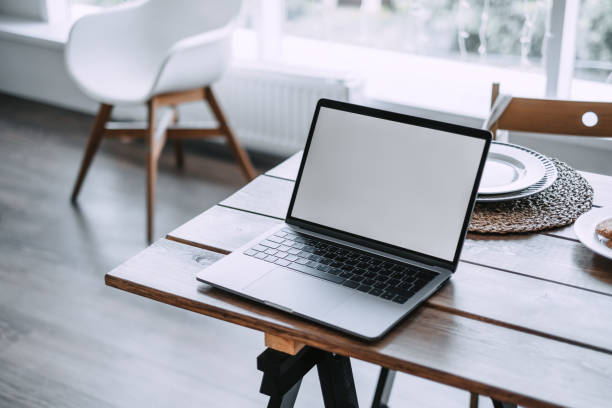 istock Laptop with a white screen on the rustic wooden table in the kitchen room 1255077071