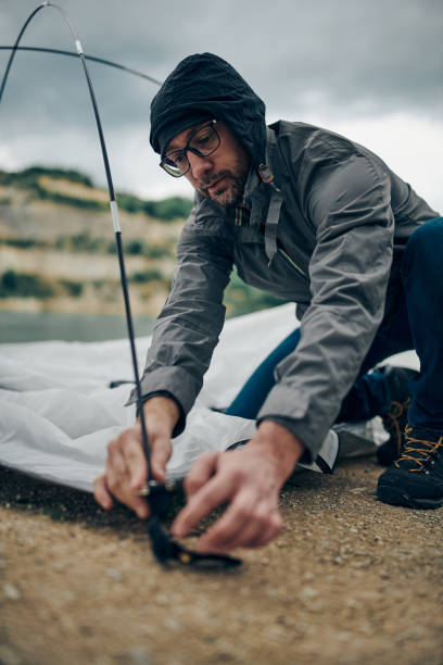istock Handsome bearded man crouching and adjusting tent in nature. Camping trip. 1255079678