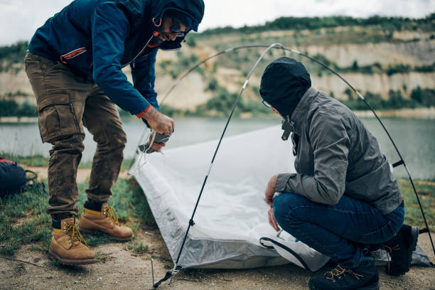 istock Two handsome men adjusting tent at camping trip in nature. 1255079745
