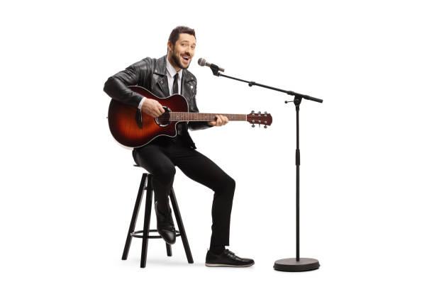 istock Man playing an acoustic guitar and singing on a microphone 1255079920
