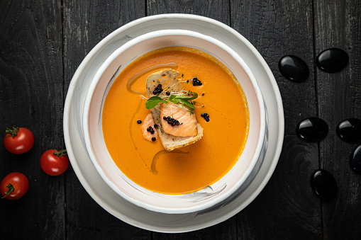 pumpkin soup with grilled salmon in a white plate. In the top restaurant