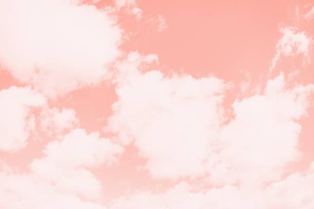 istock Pink coral color sky background with white clouds. Coral gradient background 1255081925