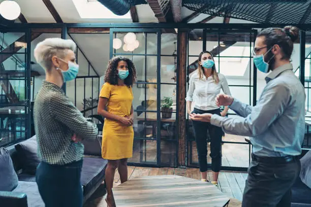 Photo of Group of entrepreneurs wearing masks and standing at a distance