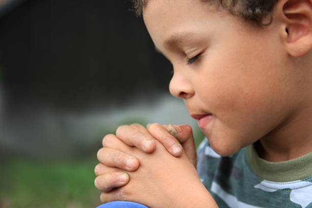 istock little boy praying stock photo 1255084975