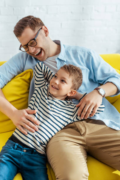 istock happy father and son laughing while sitting together at home 1255090024