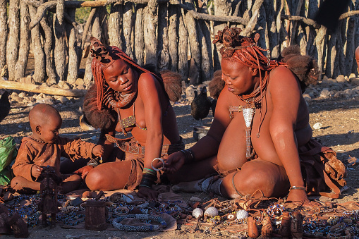 Opuwo, Namibia - Jul 08, 2019: Unidentified Himba woman with the typical necklace and hairstyle in himba tribe village