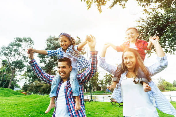 istock Loving parents carrying their children on shoulders while having fun at the park 1255091149
