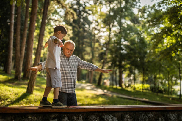 istock Grandfather helping to his grandson with balancing on bench 1255093027