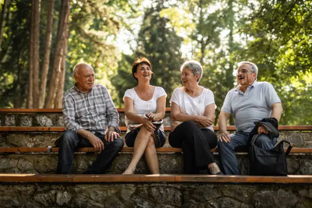 Photo of Two senior couples sitting in park, taking a break from walking