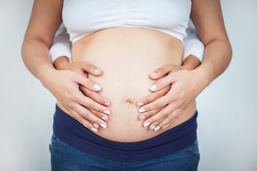 Close-up of future mother holding belly isolated on white background as expecting concept
