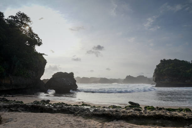 istock Sunset view with sea wave foam at Batu Bengkung Beach. Exotic paradise in Malang, East Java, Indonesia. Scenic ocean wave view of beach. 1255094272