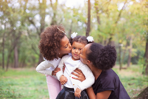 African-American mother and children hugging in the park