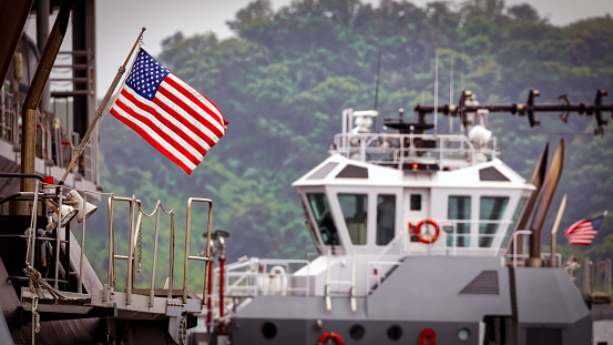 The American flag of a US Navy tugboat as it pushes a ship to its dock in Yokouska, Japan.