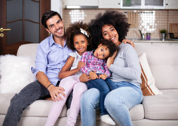 famille multiethnique heureuse sur le sofa - tickling little girls child sister photos et images de collection