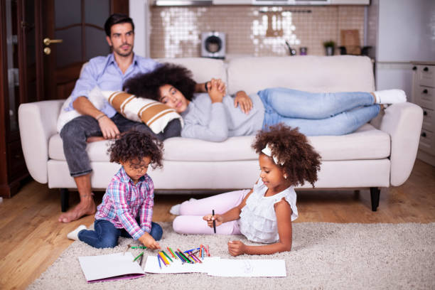 istock Kids playing on floor, parents relaxing on sofa at home 1255098159