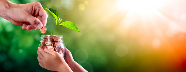 istock Hand Adding Penny To Child's Coin Jar 1255103077