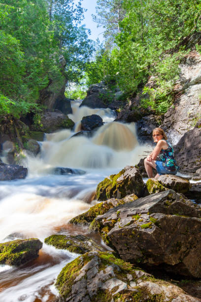 istock Lady sitting next to a waterfall called Long Slide Falls in Wisconsin during the summer 1255106378