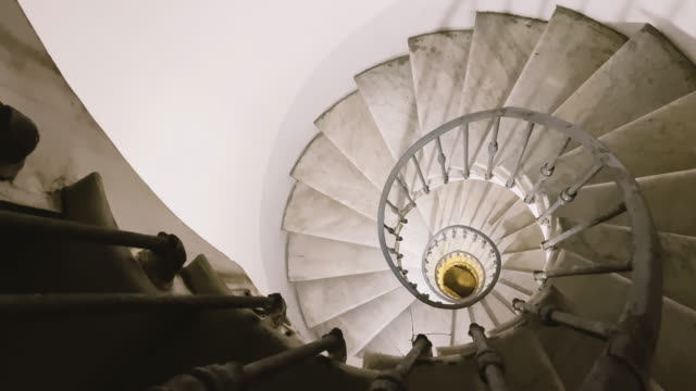 looking out from the top of an ancient spiral staircase with iron handrails and marble steps