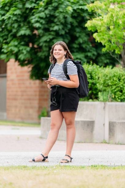 istock A thirteen year old student is walking in front of her school. 1255117839