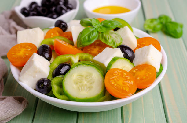 Salad raw vegetables and cheese in a dish on a wooden background. Selective focus.