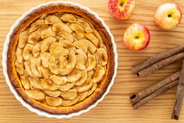 French apple tart aside Gala apples and cinnamon sticks on oak wood background. Flat lay. Top view. stock photo