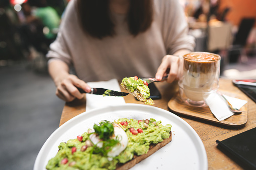 Guacamole avocado healthy food top on bread toast. Asian woman background at outdoor restaurant on day. City people lifestyle on weekend concept.
