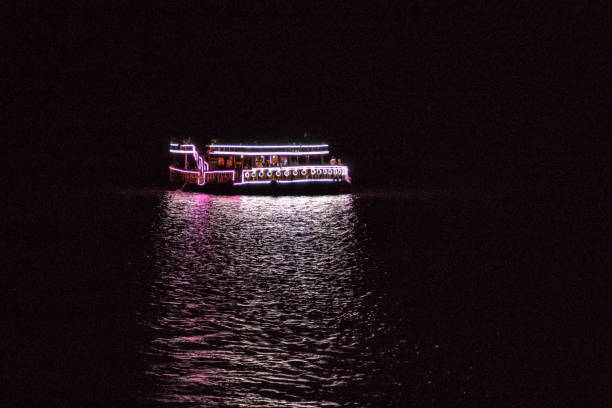 istock Kampot, Cambodia - June 15th 2018 : Tourist boat sailing river down after sunset. Beforehand, passengers have enjoyed a dinner with the views of the town 1255132003