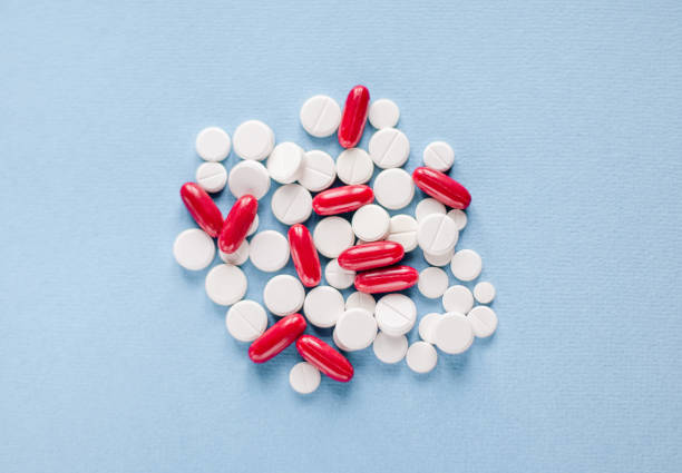 istock White and red capsules and tabletson blue background 1255137217