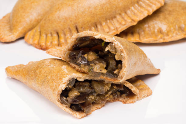 istock Two cut wholemeal baked pastry called pastel stuffed with eggplant om white background 1255139159