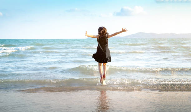 happy kid jumping on the beach in summer day