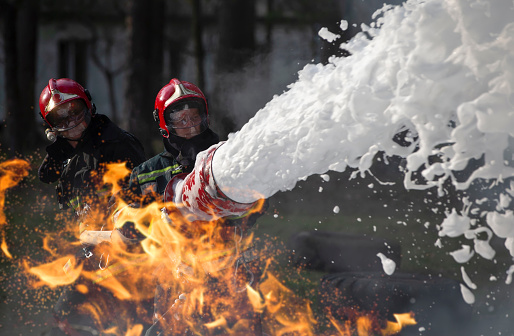 Los bomberos extinguen un incendio. Socorristas con mangueras contra incendios en humo y fuego. photo