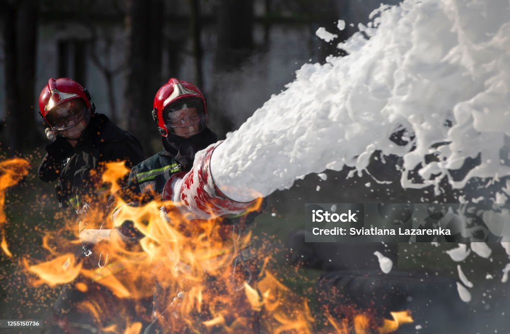 Firefighters extinguish a fire. Lifeguards with fire hoses in smoke and fire. Firefighter Stock Photo