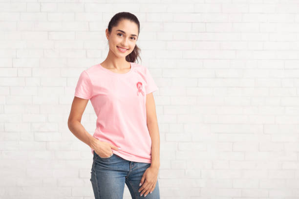 volunteer in t-shirt with ribbon symbol standing over white wall - t shirt shirt pink blank imagens e fotografias de stock