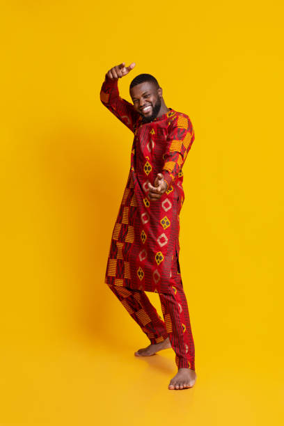 istock Funny handsome guy in african dress posing over yellow 1255152534