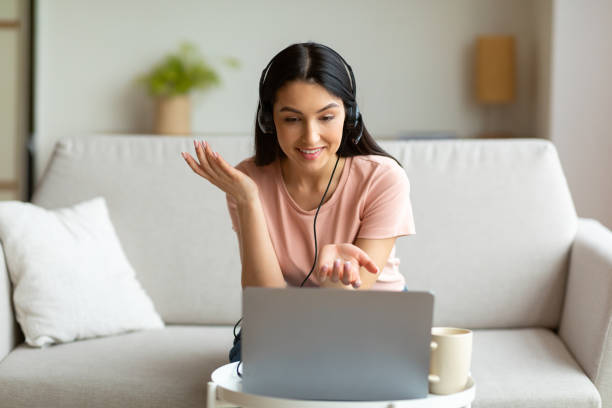 istock Lady Making Video Call On Laptop Wearing Headset Sitting Indoors 1255153688