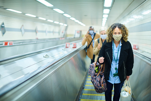 a female commuter on her   way to work by underground wearing a face mask